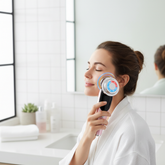 Woman using facial massager in bathroom lifestyle photo